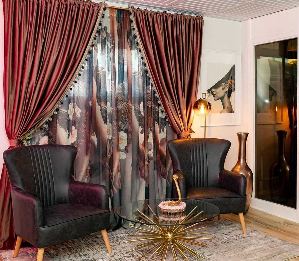 Elegant room with dark chairs, floral curtains, stylish lamp, and decor accents.