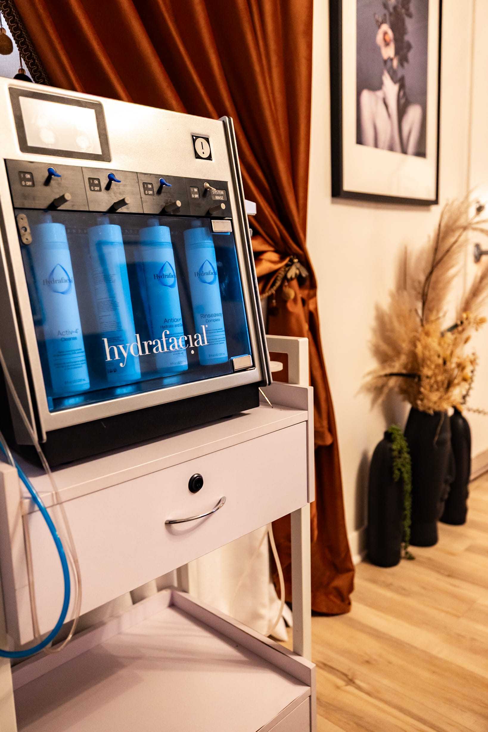 Hydrafacial machine in a spa room with a decorative backdrop and plants.