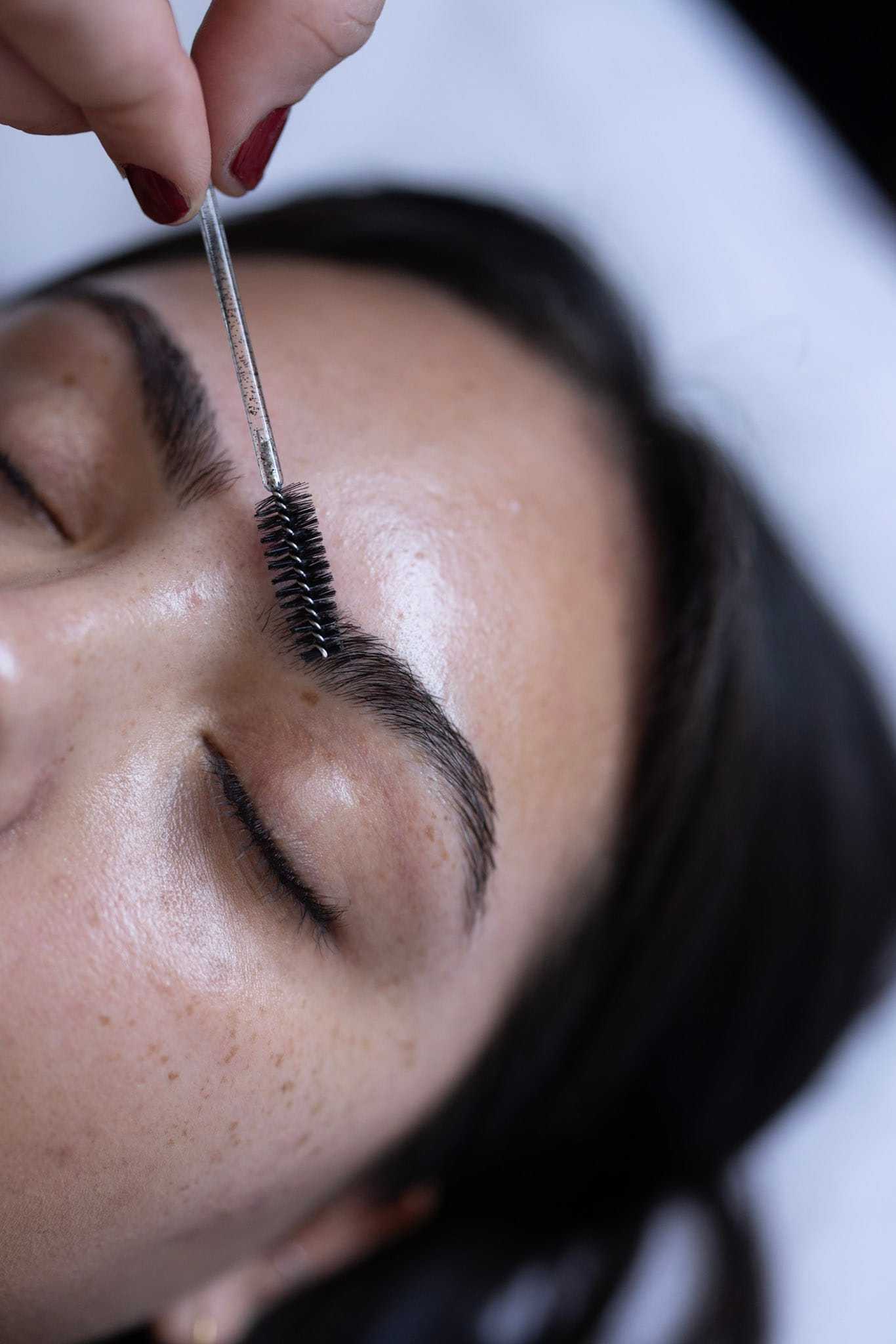 Applying eyebrow brush on closed eyes for grooming.